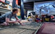 Man arranging a metal grid amid theatrical props and recording equipment