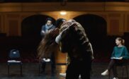 Actors rehearse a choreographed stage-combat movement in a theater