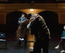 Actors rehearse a choreographed stage-combat movement in a theater