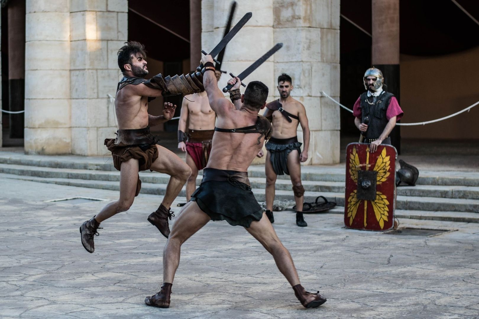Actors in Roman-style costumes perform a choreographed sword fight