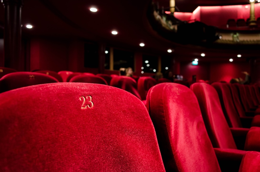 Close-up view of red velvet theater seats with visible seat number 23, showing the numbered seating system used in professional theater venues.